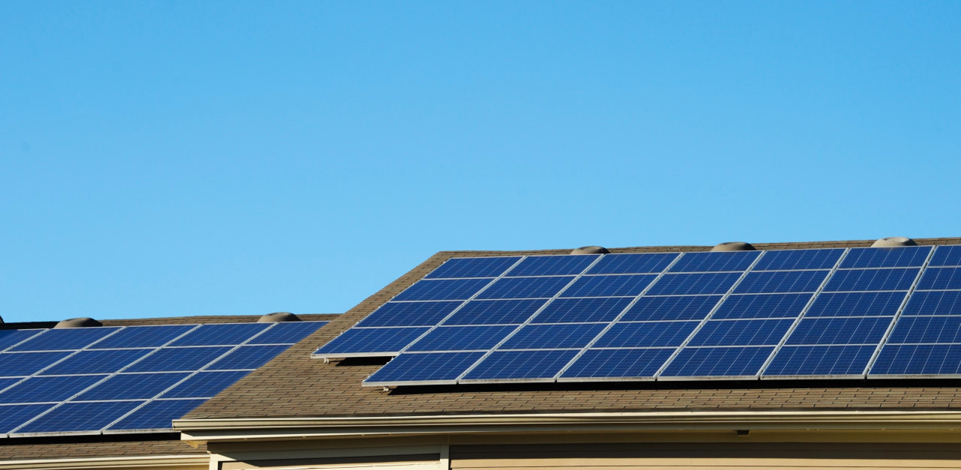 Solavita Solar technician wearing safety gear performing panel maintenance on a rooftop PV system under clear skies