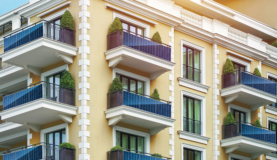 Modern apartment building with solar panel railings on balconies, integrating renewable energy into residential architecture.